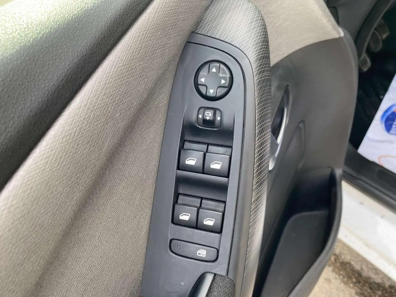 Vue rapprochée de la commande des vitres électriques sur la porte avant gauche d’un Citroën Grand C4 Picasso blanc.