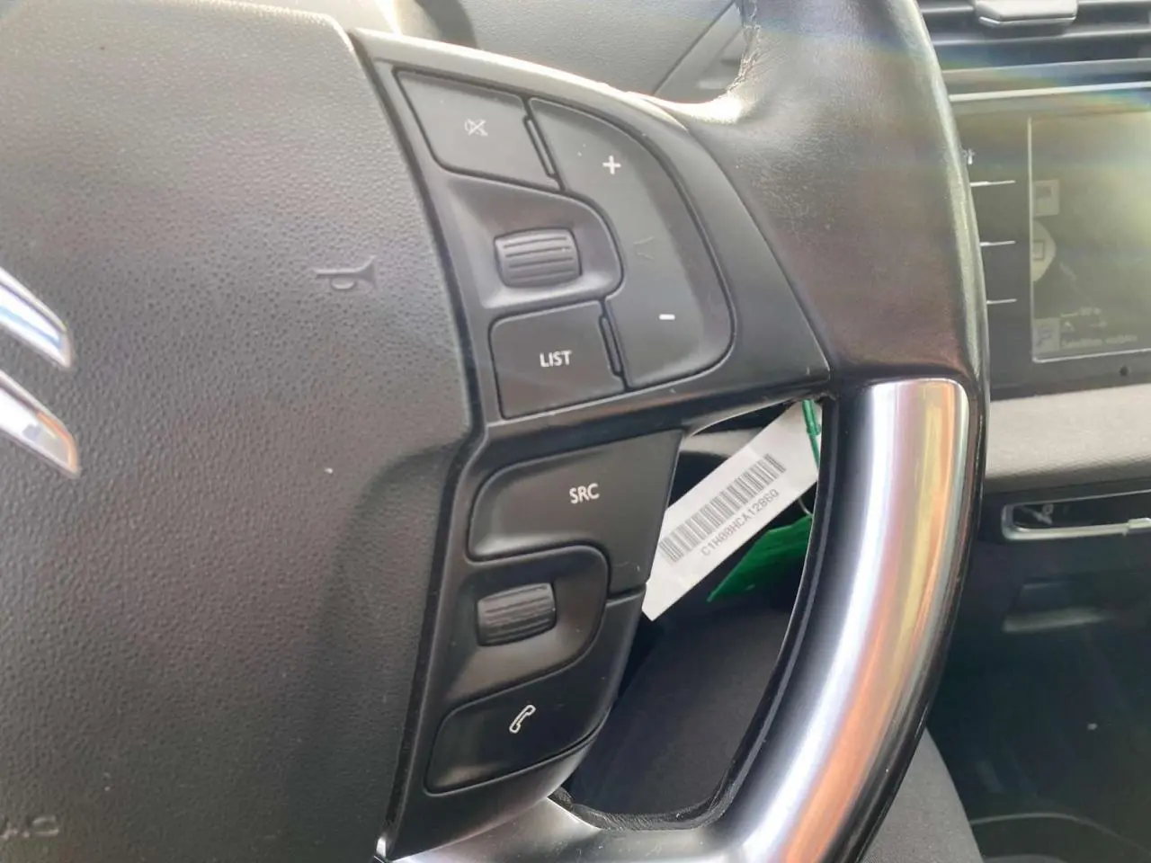 Gros plan sur le volant cuir noir du Citroën Grand C4 Picasso 2015, avec commandes audio et écran tactile en arrière-plan.