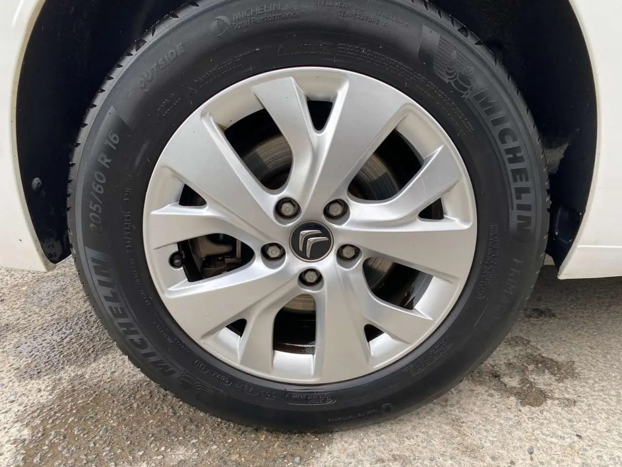 Gros plan sur la jante alliage 16 pouces Notos argentée et pneu Michelin d'un Citroën Grand C4 Picasso blanc.