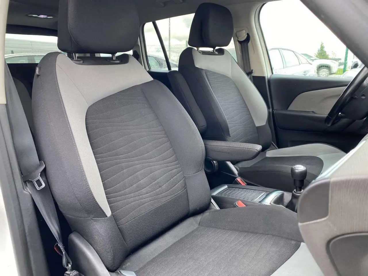 Vue intérieure côté avant droit du Citroën Grand C4 Picasso 2015, sièges tissu gris et console centrale avec levier de vitesses.