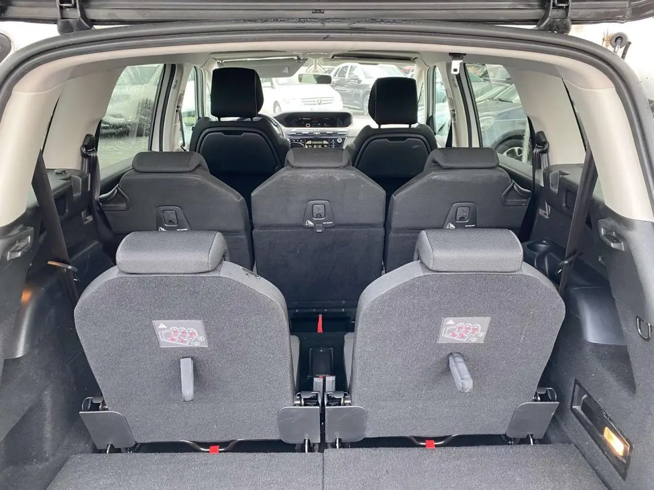 Vue arrière intérieure du Citroën Grand C4 Picasso blanc 7 places, montrant les sièges rabattus et l'habitacle spacieux.