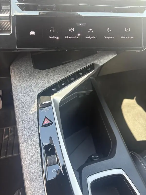 Vue rapprochée de la console centrale du Peugeot 3008 Hybrid 136 e-DCS6 Allure 2025, avec tissu gris clair et commandes tactiles.