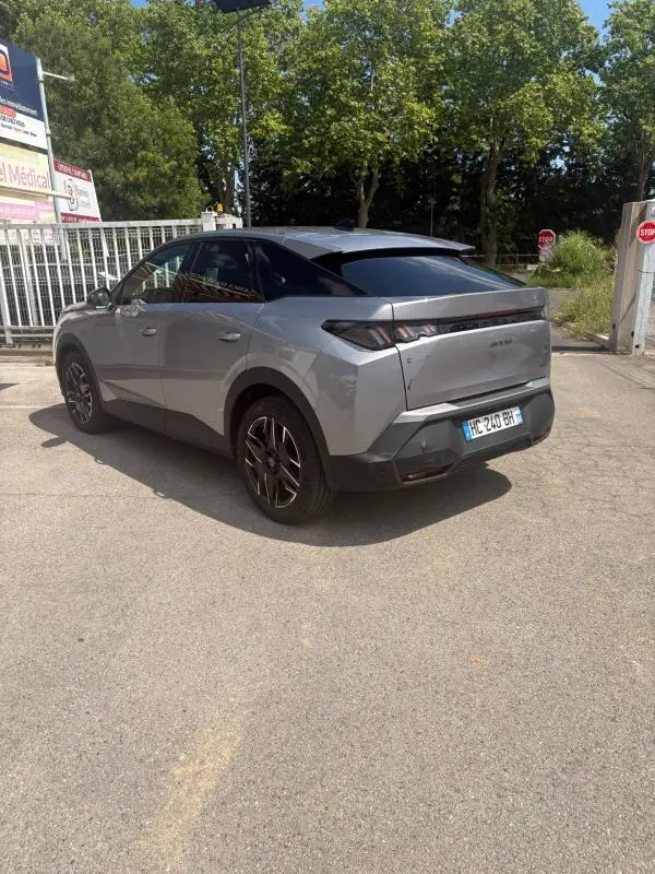 Vue 3/4 arrière droite du Peugeot 3008 Hybrid gris clair 2025 avec toit noir et feux arrière distinctifs.