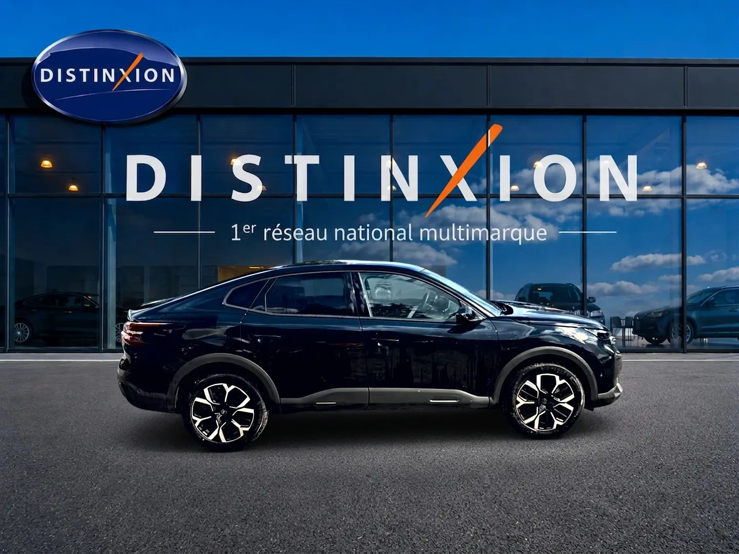 Profil côté gauche d'une Citroën C4 X noire 2025 avec jantes alu distinctives, devant une vitrine Distinxion.