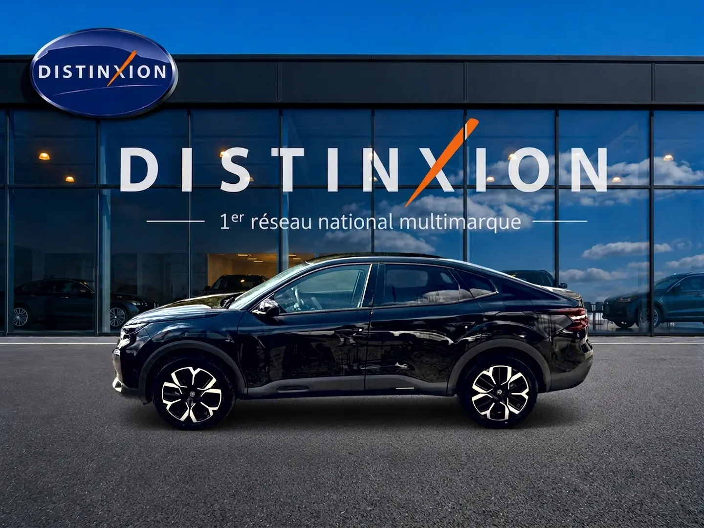 Citroën C4 X noire vue de profil côté gauche, avec jantes alu et silhouette élancée devant showroom Distinxion.