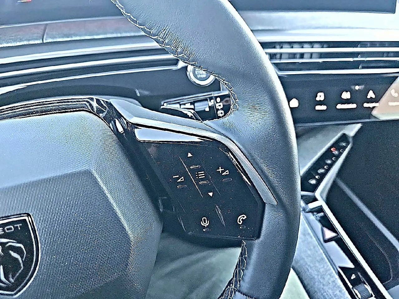 Gros plan sur le volant cuir multifonction noir du Peugeot 5008 Hybrid 145 allure e-dcs6 avec commandes vocales et téléphone.