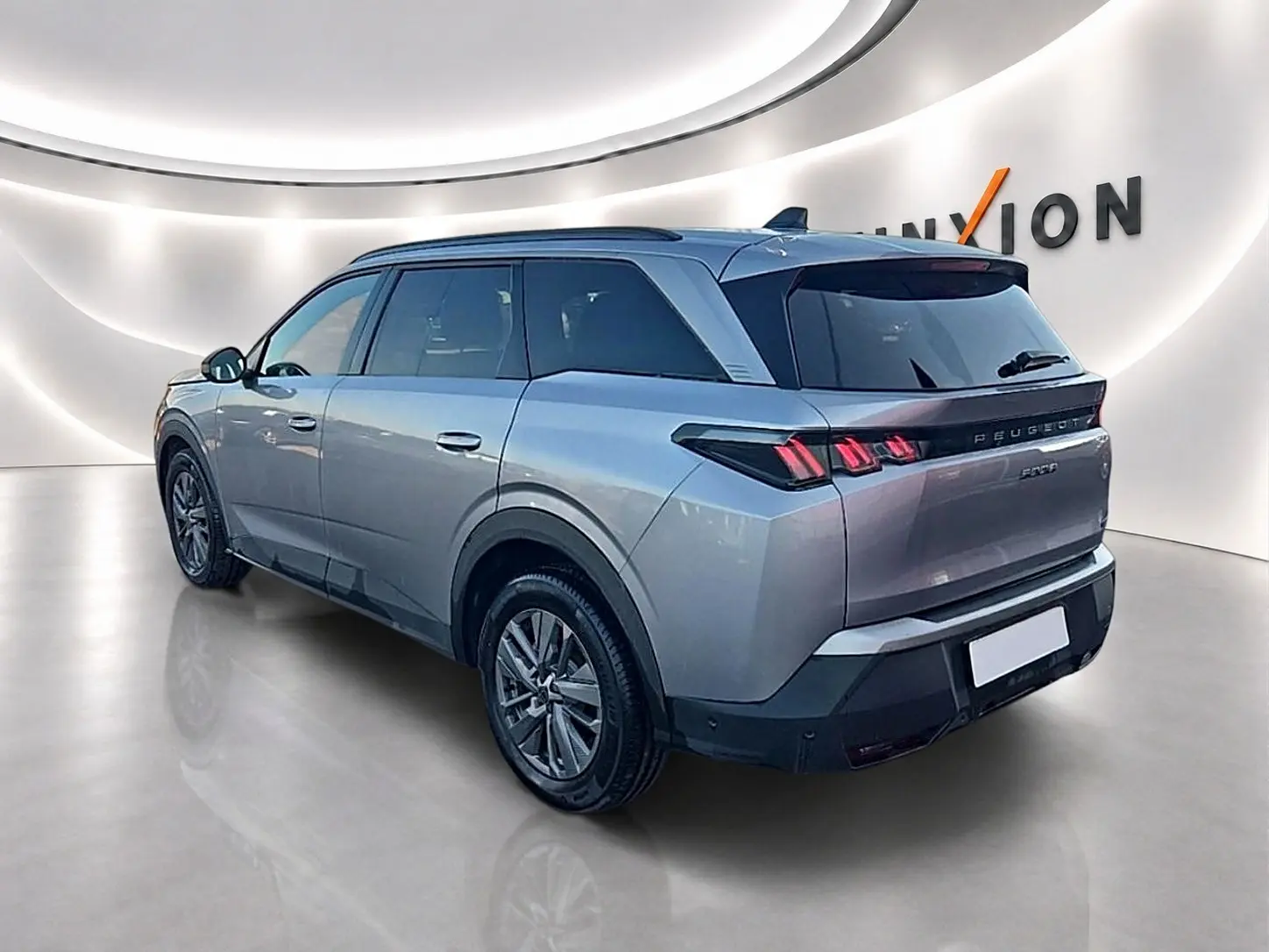 Peugeot 5008 gris artense vue 3/4 arrière droit dans un showroom lumineux avec feux arrière LED distinctifs.