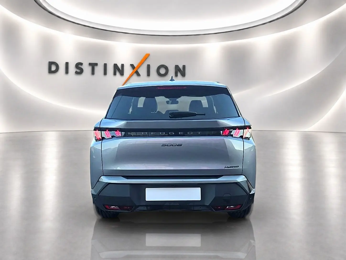 Vue arrière d'un Peugeot 5008 Hybrid 145 allure e-dcs6 gris artense dans un showroom lumineux avec logo Distinxion.