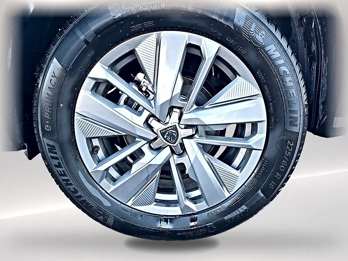 Gros plan sur la jante alu argentée du Peugeot 5008 Hybrid 145 allure e-dcs6 avec pneu Michelin noir.