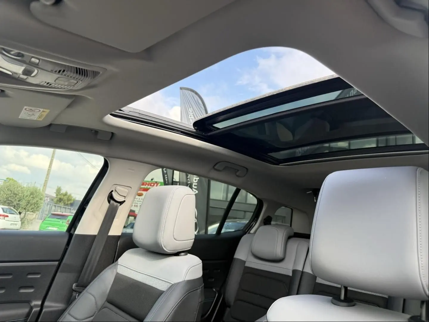 Intérieur du Citroën C5 Aircross 2024 noir métal, vue sur les sièges avant et arrière avec toit ouvrant panoramique ouvert.