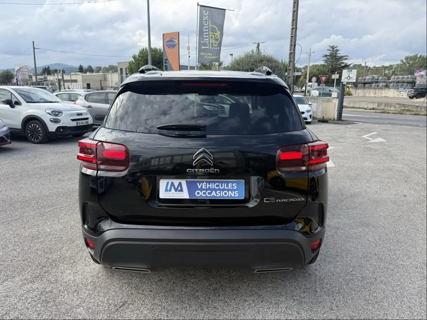 Vue arrière d'un Citroën C5 Aircross noir métal 2024 avec feux rouges et logo distinctif sur parking extérieur.
