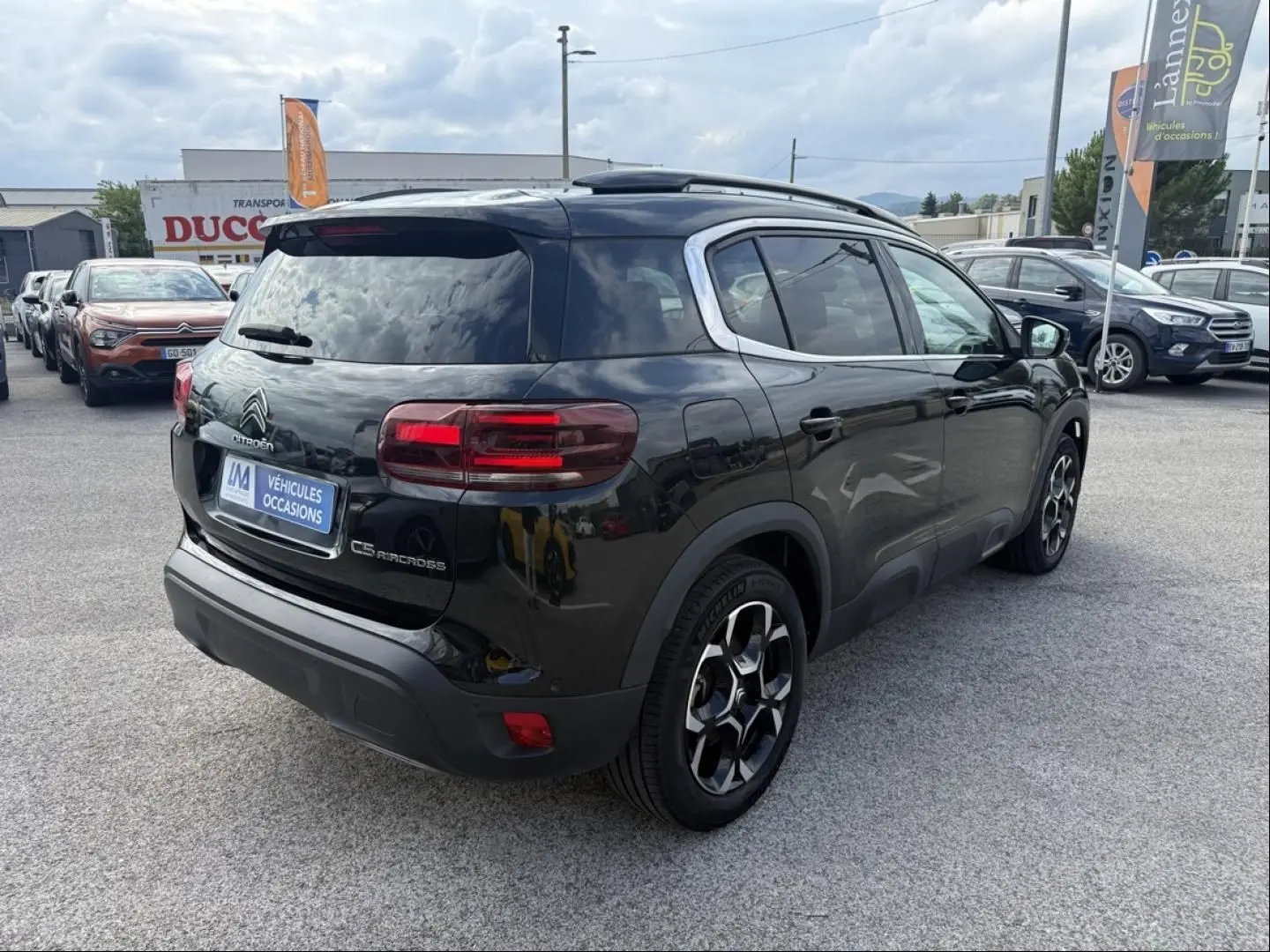 Vue 3/4 arrière droite d’un Citroën C5 Aircross noir métal 2024 avec jantes spécifiques et toit ouvrant visible.