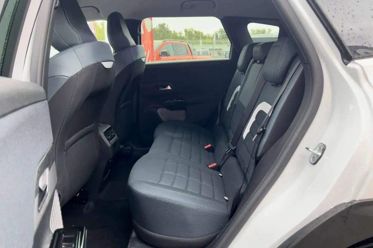 Vue intérieure arrière côté droit du Citroën C5 Aircross Hybrid 2026 avec banquette noire et détails blancs.