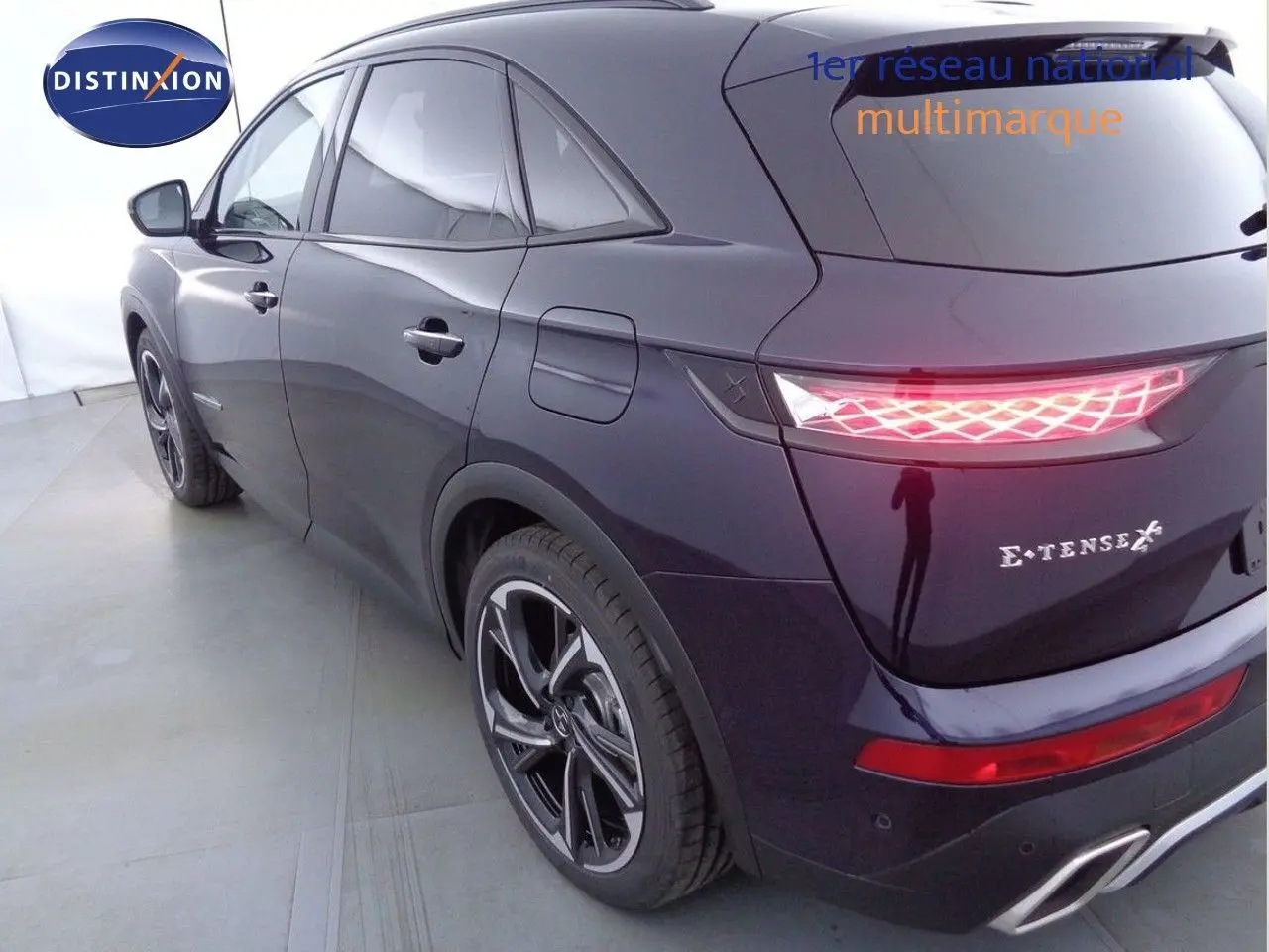 Vue 3/4 arrière droite du DS7 Crossback E-TENSE 300CH en bleu encre métal avec feux arrière LED allumés.