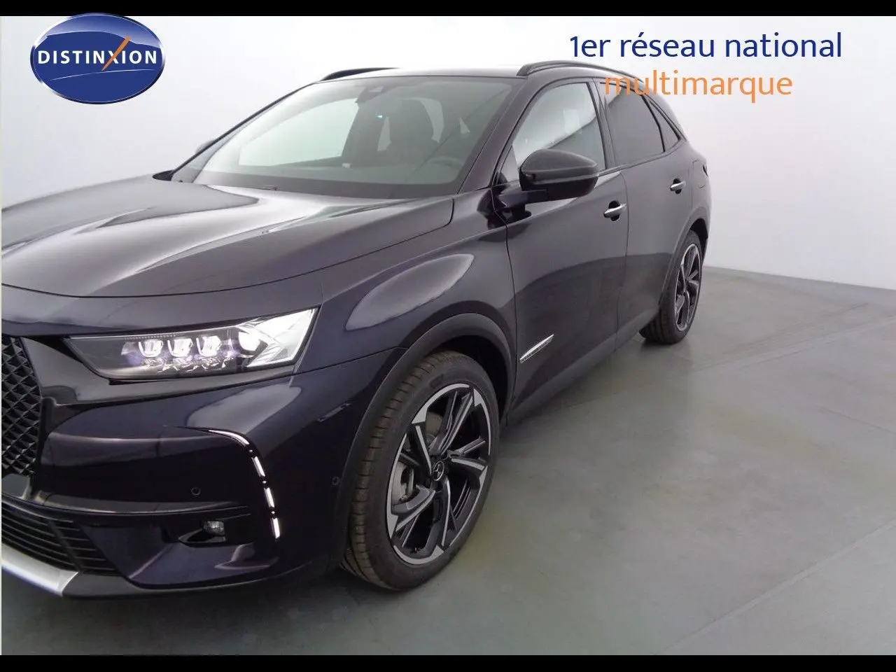 Vue 3/4 avant droit du DS7 Crossback E-TENSE 300CH en bleu encre métal avec ses phares LED allumés et jantes noires.