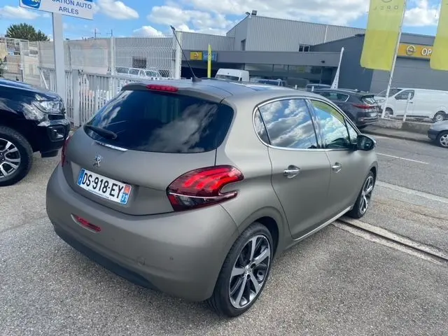 Vue 3/4 arrière droite d'une Peugeot 208 1.2 PureTech Feline 2015 en gris mat avec vitres teintées et jantes alliage.