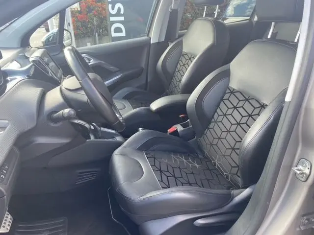 Vue intérieure côté conducteur de la Peugeot 208 1.2 PureTech Felline 2015, sièges noirs avec motifs géométriques.
