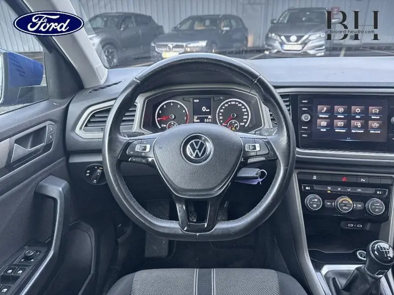 Vue intérieure centrée sur le volant multifonction noir du Volkswagen T-Roc 1.0 TSI 2021 avec tableau de bord et écran tactile.