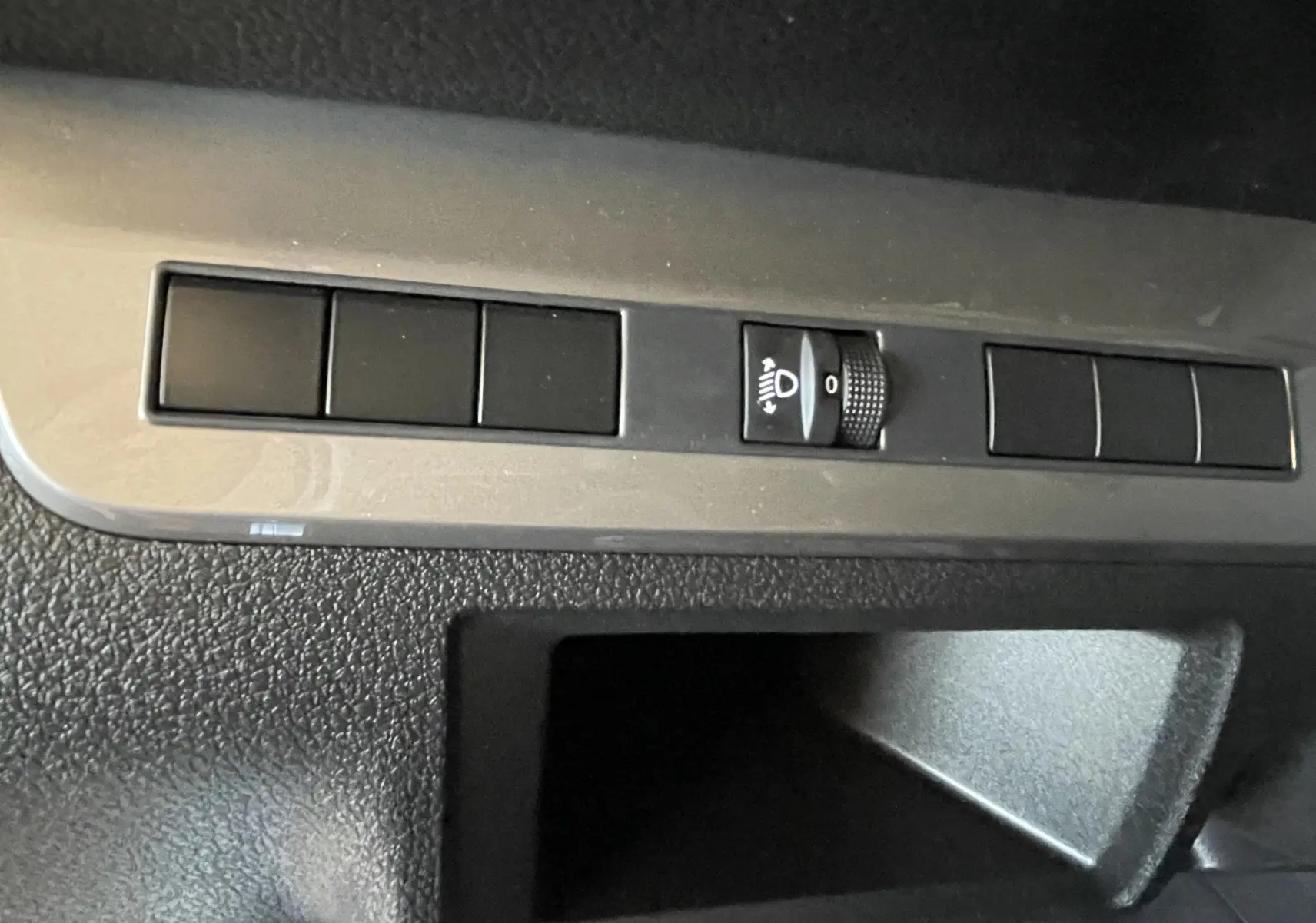 Détail intérieur du tableau de bord du Citroën Jumpy Cabine Approfondie, commande de réglage des phares sur bande grise.
