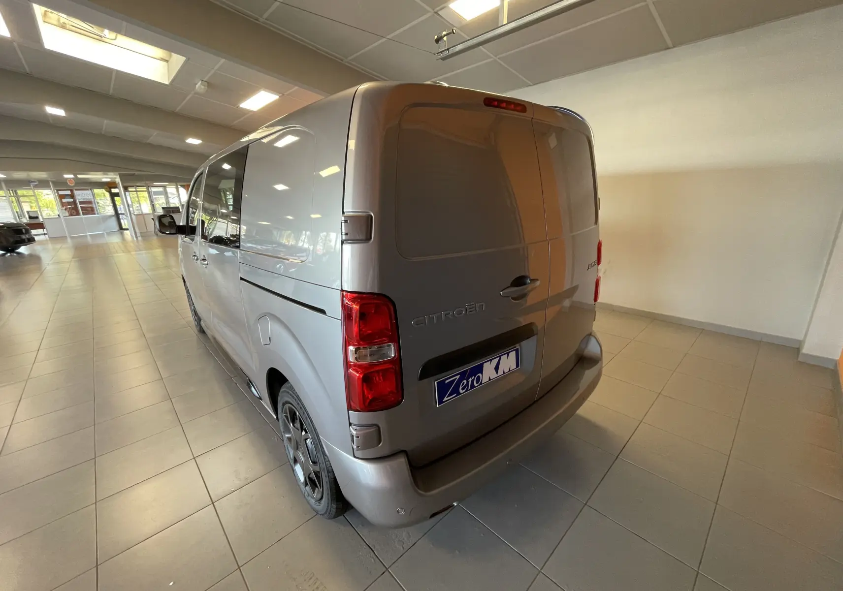 Vue 3/4 arrière gauche d’un Citroën Jumpy Cabine Approfondie gris Artense avec porte latérale coulissante en showroom.