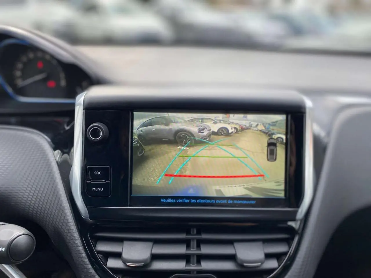 Écran central du Peugeot 2008 gris platinium montrant l’image de la caméra de recul avec lignes de guidage colorées.