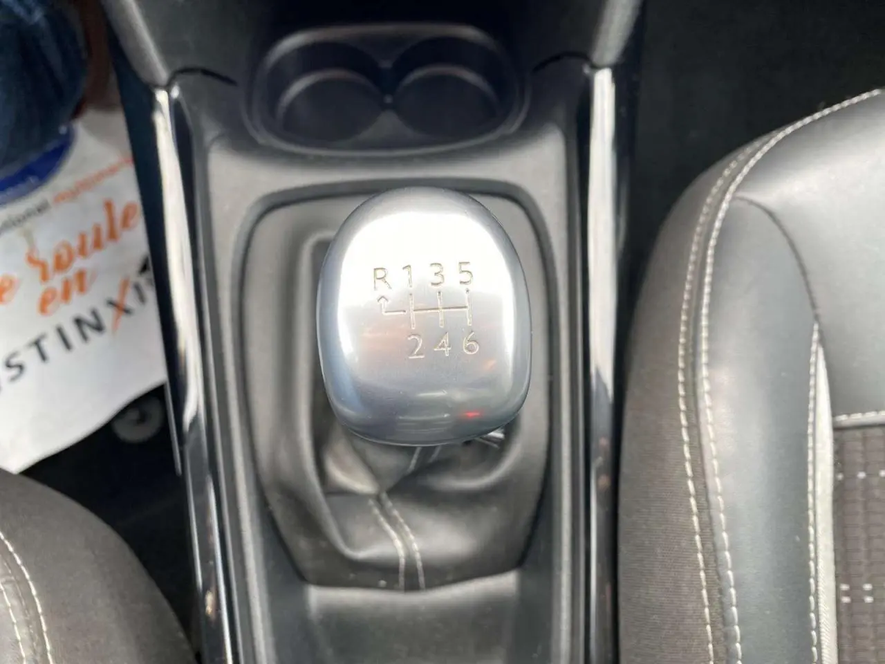Vue rapprochée du levier de vitesses manuel gris argenté de la Peugeot 2008, entouré de sièges noirs.