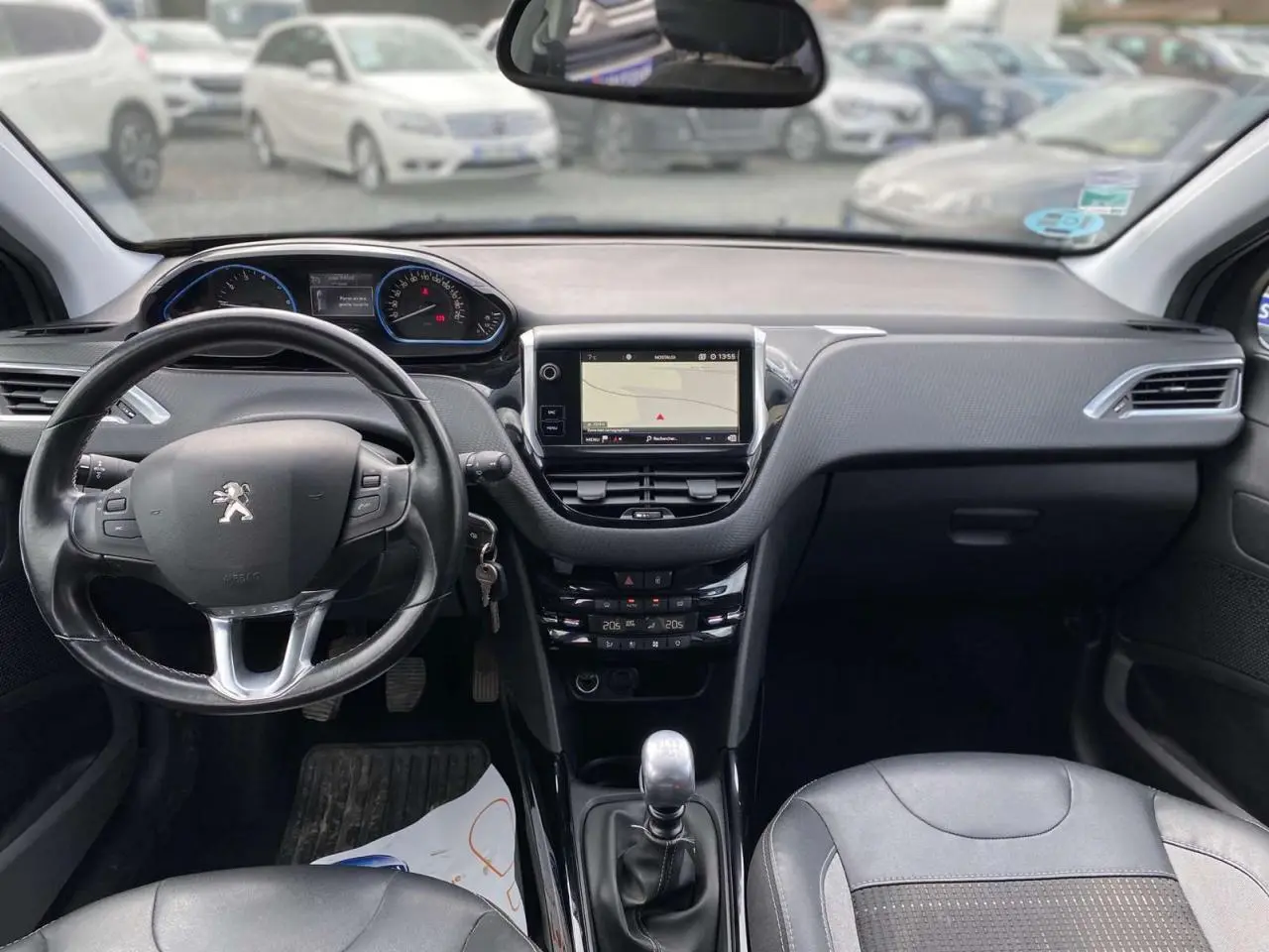 Vue intérieure avant du Peugeot 2008 gris platinium de 2019, avec tableau de bord moderne et boîte manuelle visible.