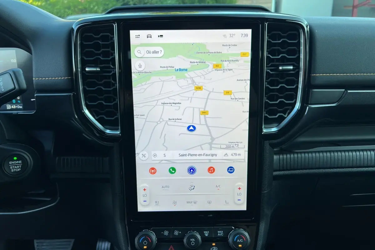 Vue rapprochée de la console centrale du Ford Ranger PHEV 2025 avec écran tactile GPS et commandes climatisation.