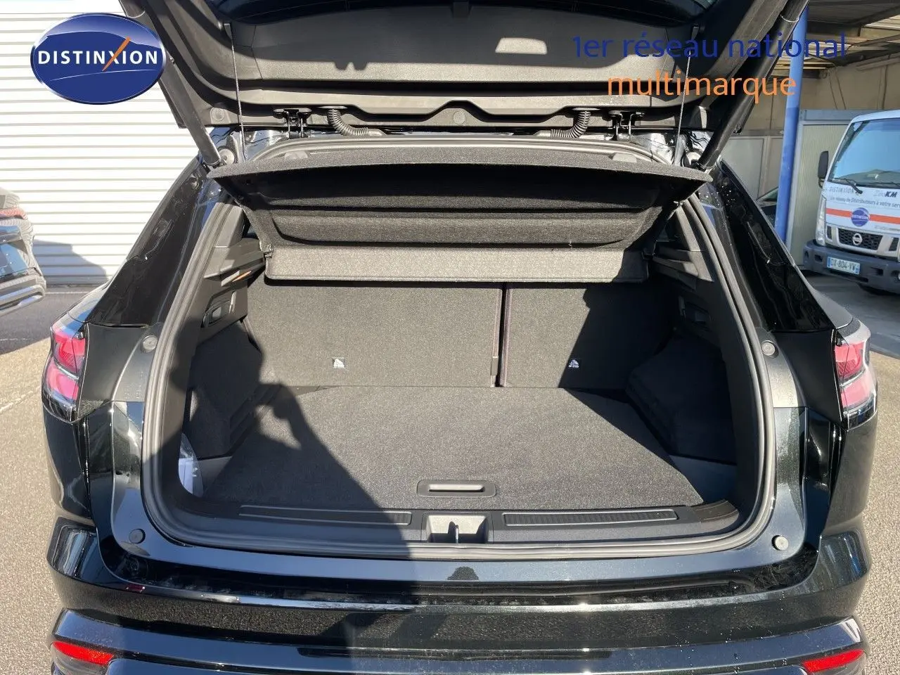 Coffre ouvert vu de l'arrière d'un Renault Austral noir étoile métal, montrant un espace de chargement spacieux et propre.