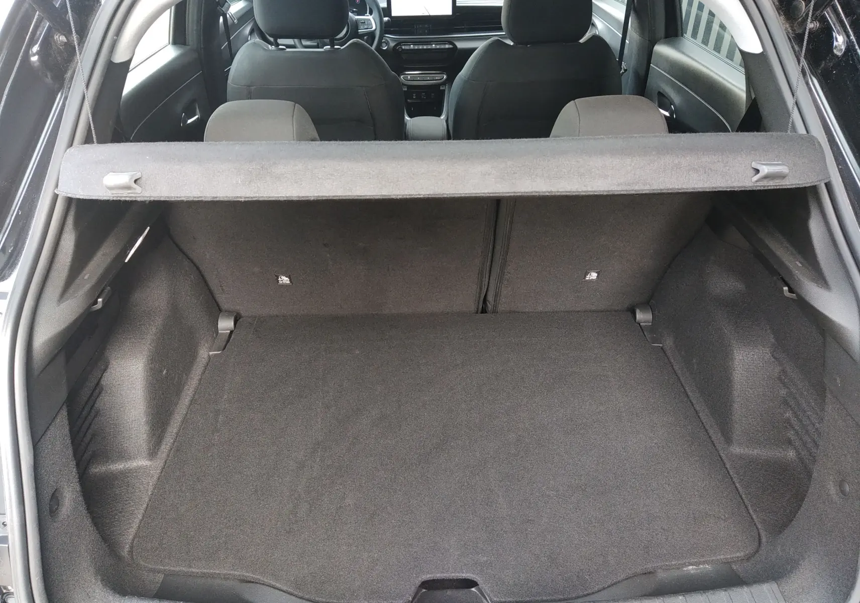 Coffre ouvert d'une FIAT 600 noire, vue de l'arrière montrant l'espace de chargement et les sièges avant.