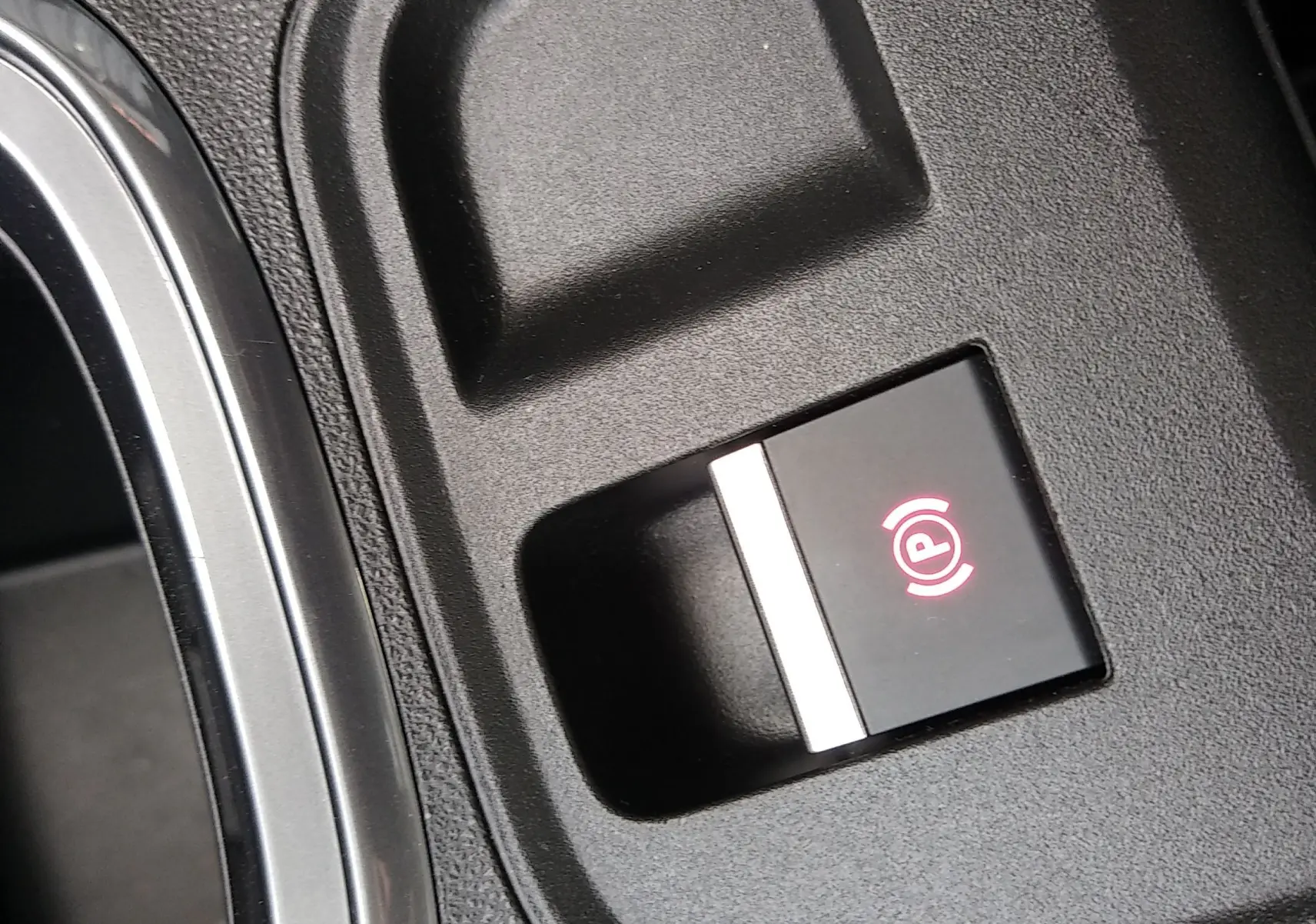 Gros plan sur le bouton de frein à main électronique rouge dans l'habitacle noir d'une FIAT 600 hybride 2025.