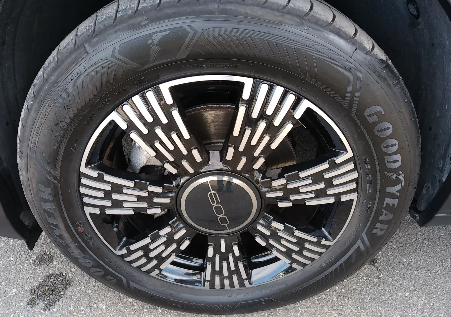 Gros plan sur la jante noire et argentée d'une FIAT 600 noire, mettant en valeur le logo central et le pneu Goodyear.