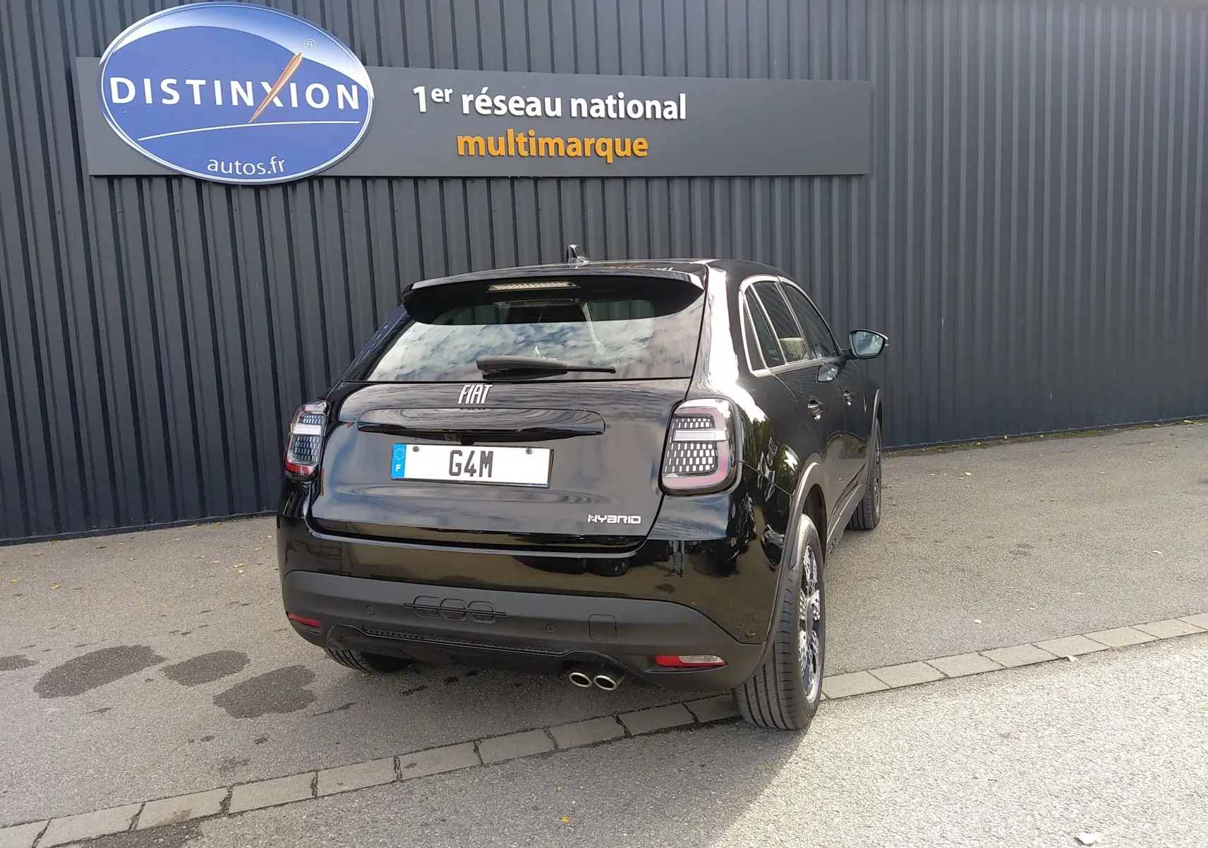 Vue 3/4 arrière droite d'une FIAT 600 noire hybride 2025, avec feux arrière LED et double sortie d'échappement.
