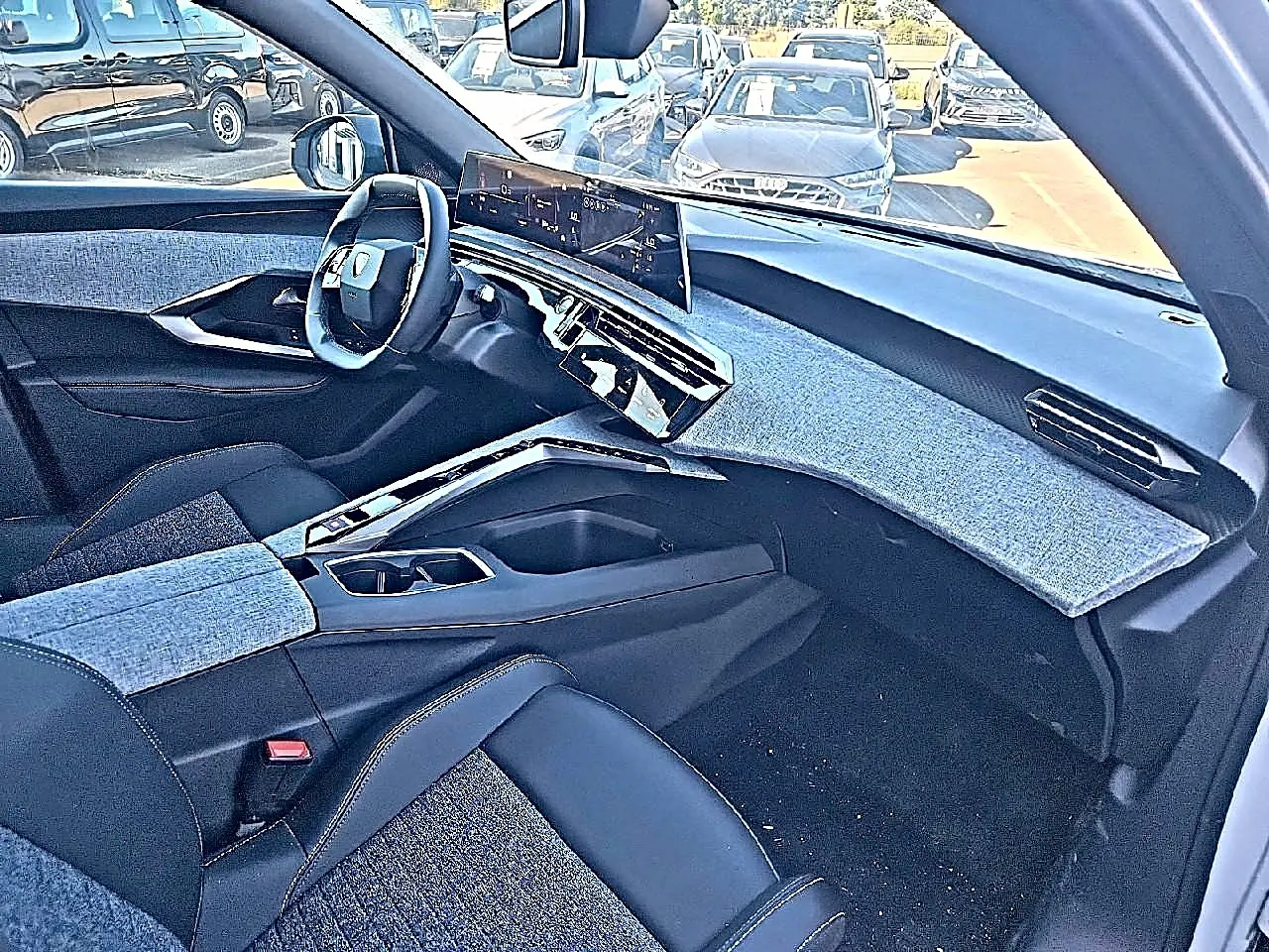 Vue intérieure côté passager du Peugeot 5008 Hybrid 145 allure 2025 avec tableau de bord bleu et sièges noirs.