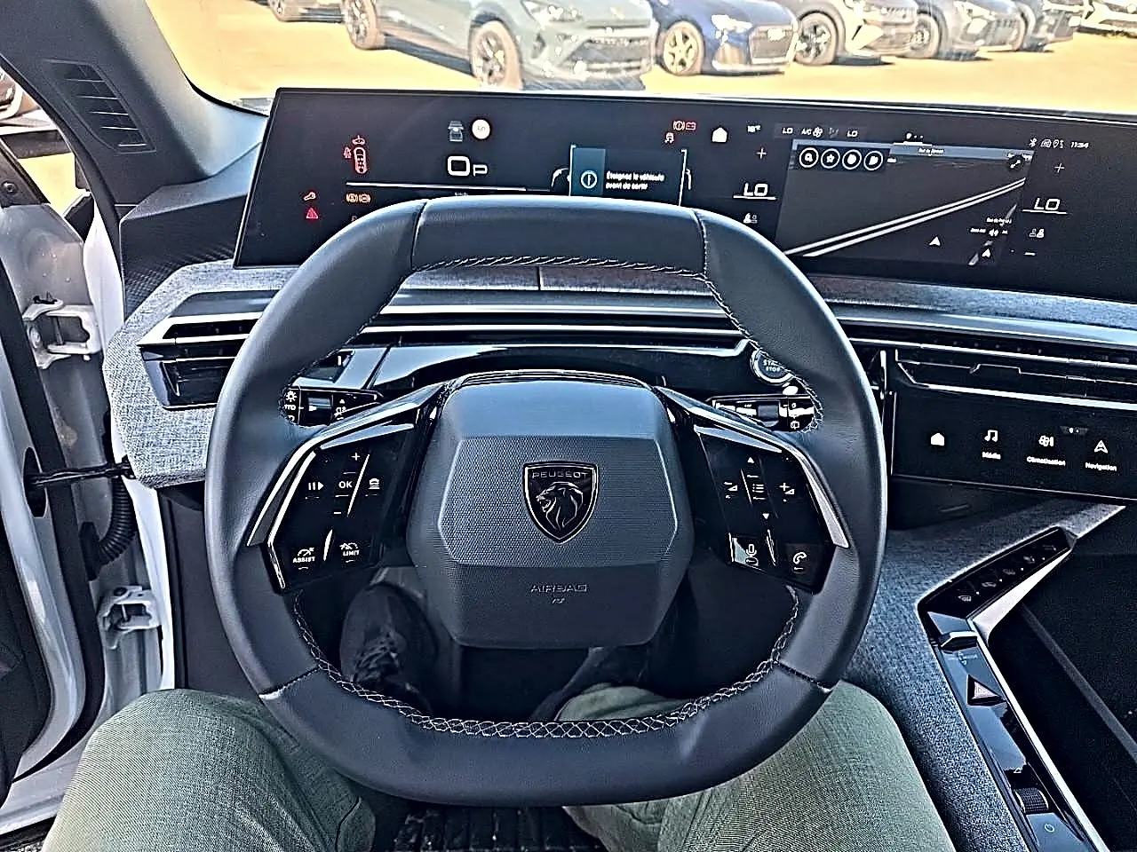 Vue intérieure centrée sur le volant cuir multifonction noir d’un Peugeot 5008 blanc avec tableau de bord numérique.