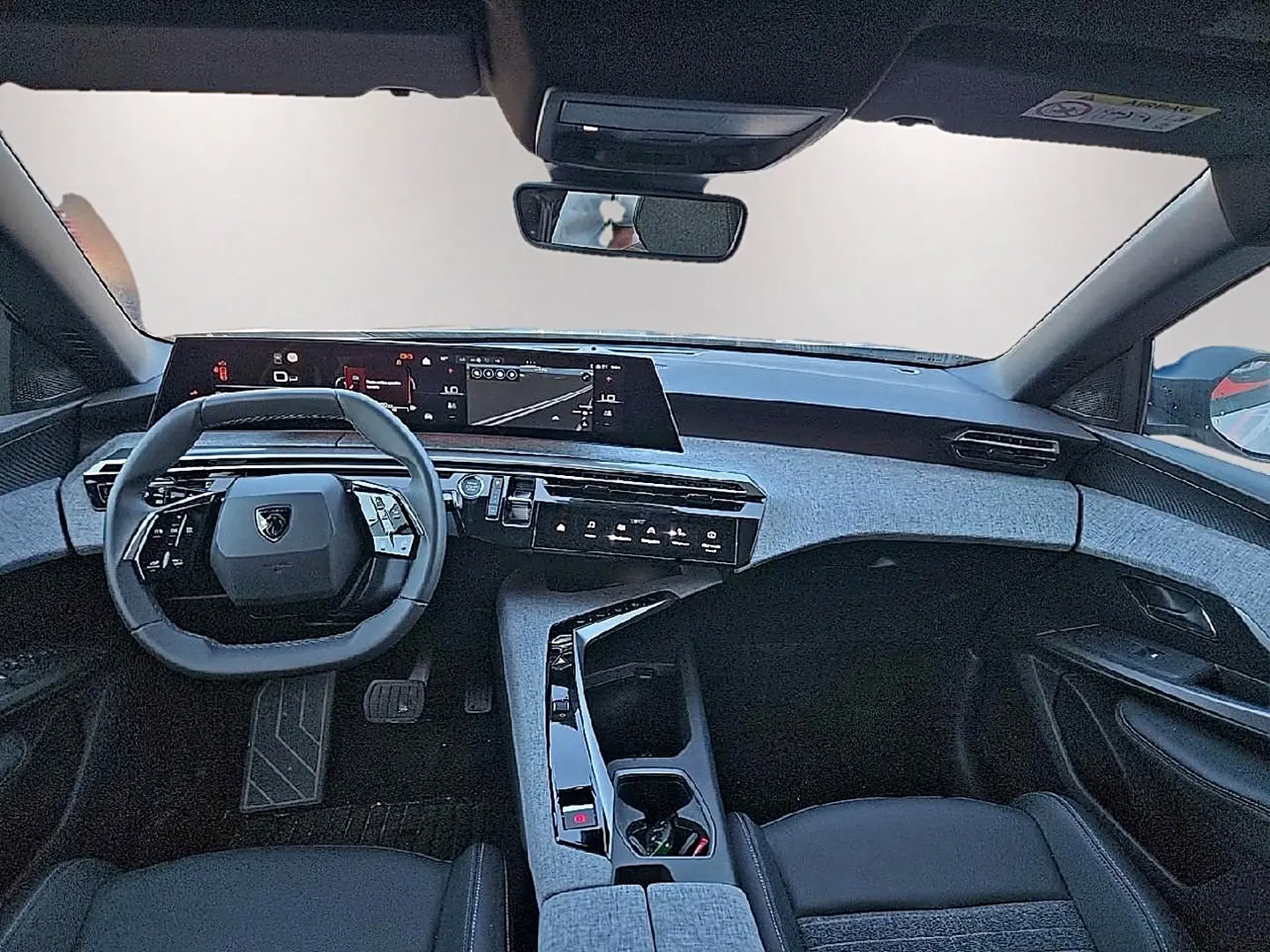 Vue intérieure avant du Peugeot 5008 Hybrid blanc 2025, avec tableau de bord numérique et volant cuir multifonction.