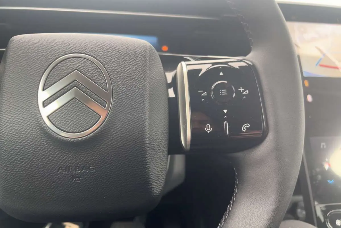Gros plan sur le volant cuir multifonctions du Citroën C5 Aircross Hybrid 145 Plus, avec logo chrome et commandes tactiles.