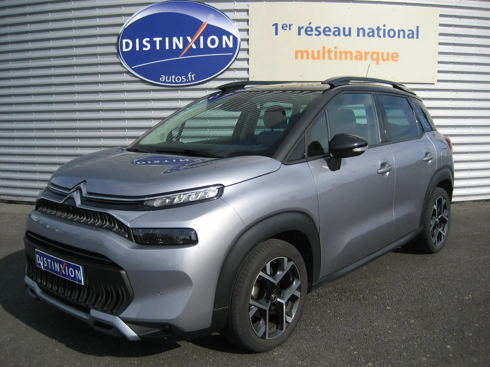 Citroën C3 Aircross gris vue 3/4 avant droit, avec toit noir et jantes alliage distinctives.