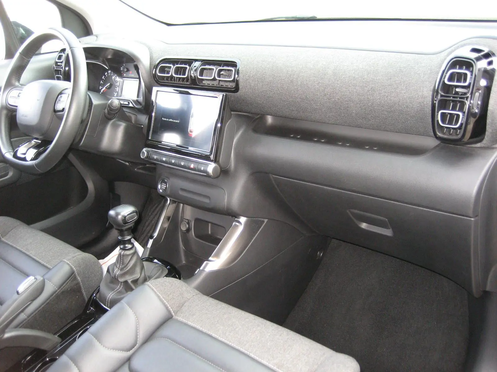 Vue intérieure côté passager du tableau de bord gris et noir du Citroën C3 Aircross II 2022 avec boîte manuelle.