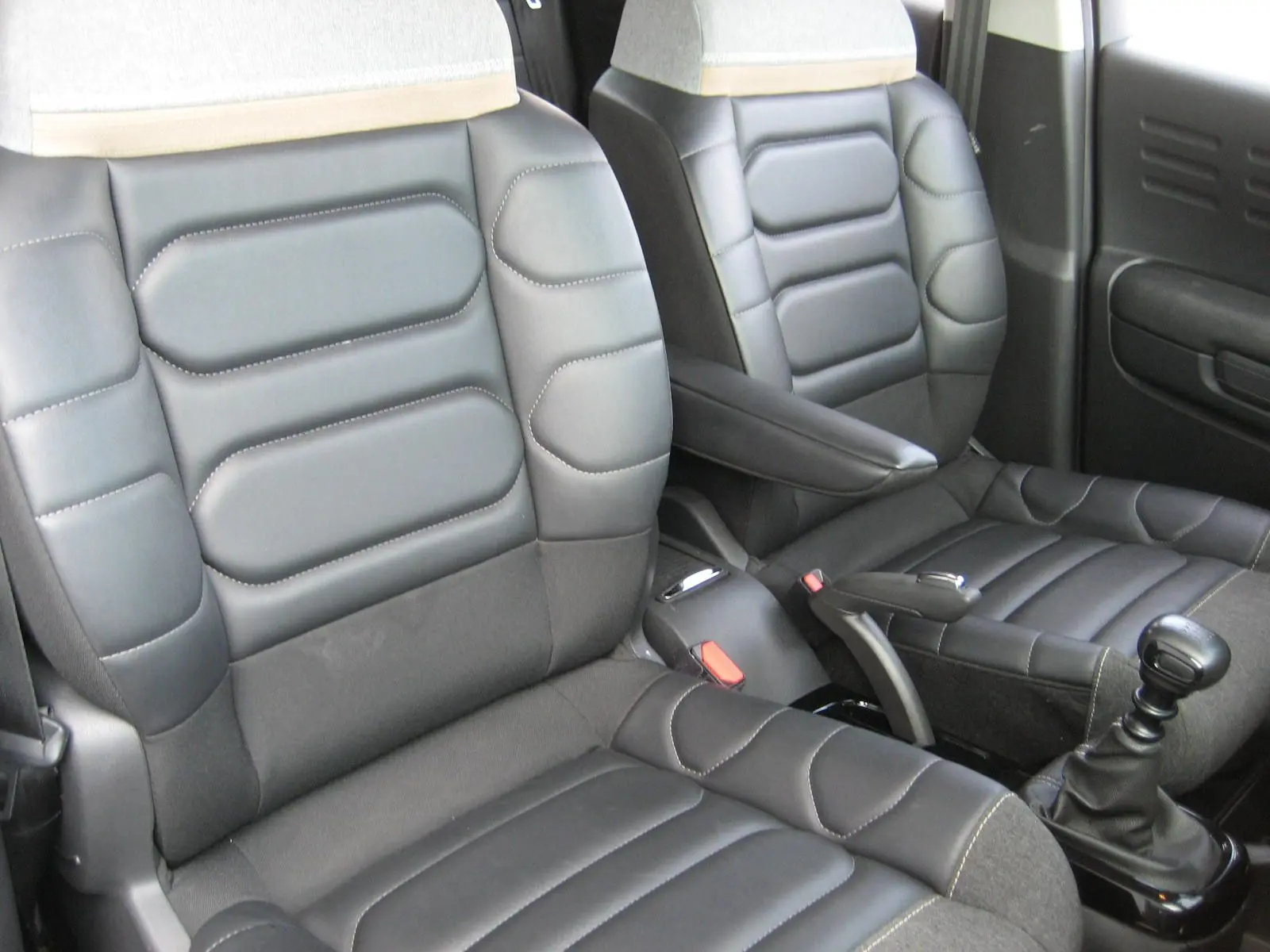 Vue rapprochée des sièges avant en cuir noir et tissu gris du Citroën C3 Aircross 2022 avec levier de vitesse manuel.