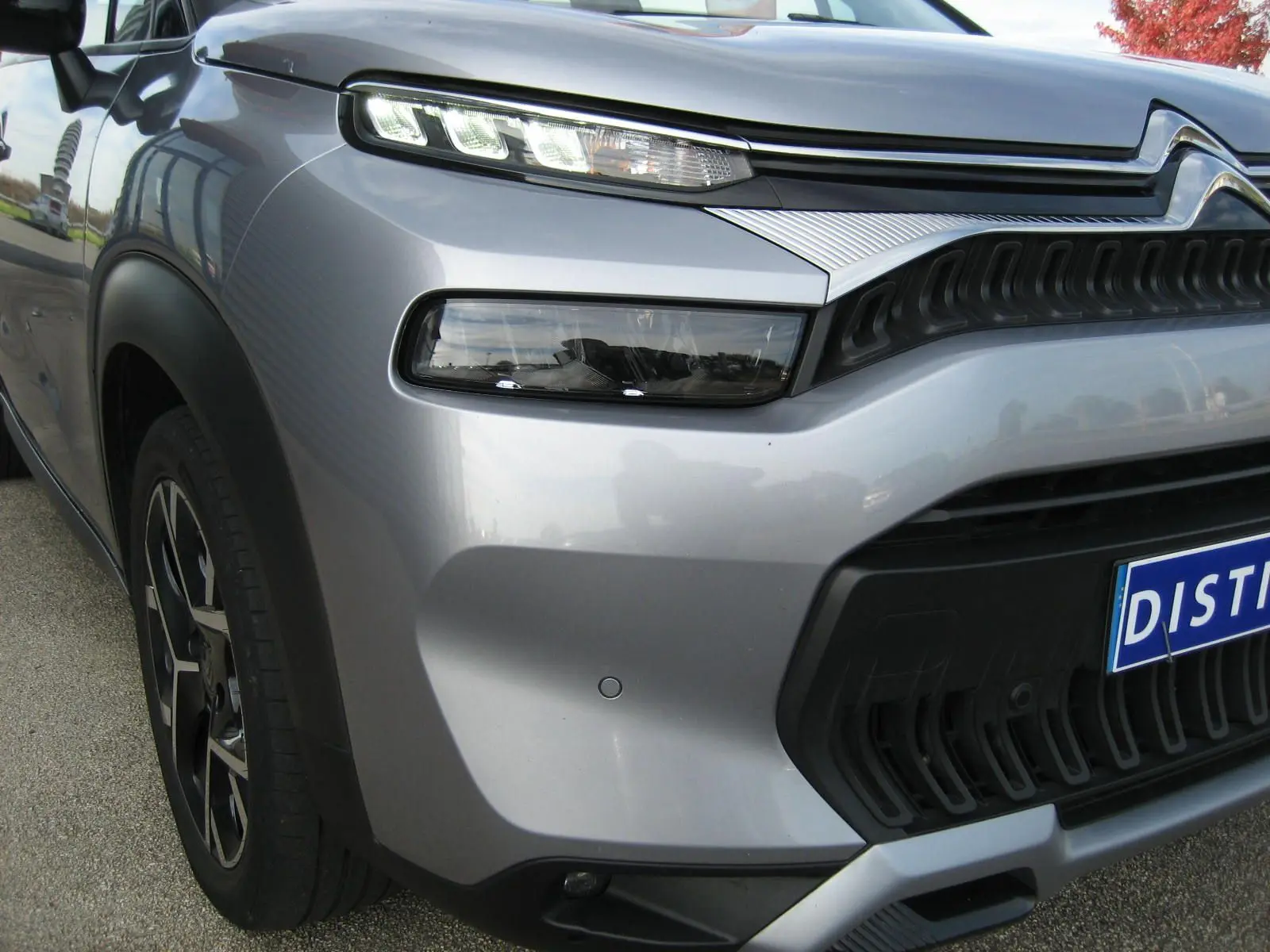 Gros plan sur l'avant droit gris du Citroën C3 Aircross II avec ses phares LED étirés et sa calandre noire texturée.