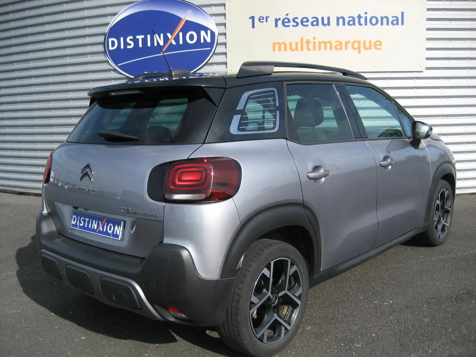 Vue 3/4 arrière droite d'un Citroën C3 Aircross gris 2022 avec toit noir et jantes alliage distinctives.