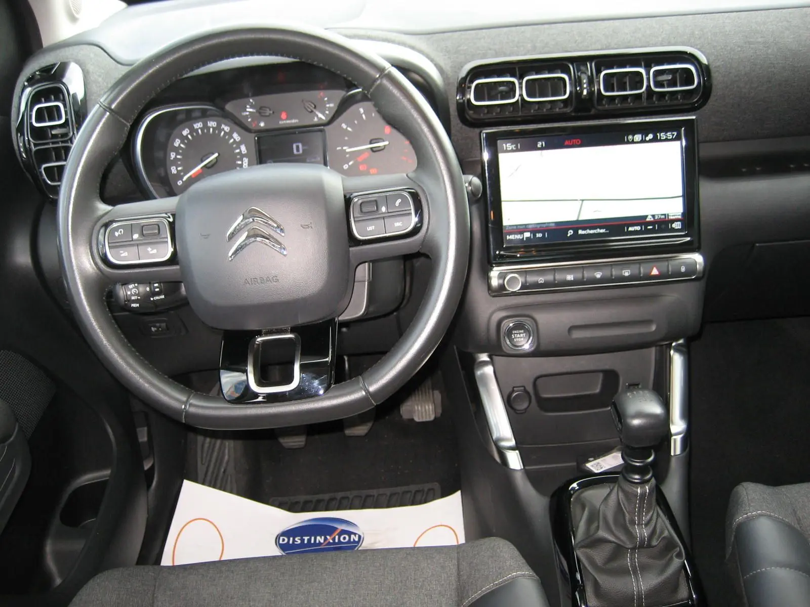 Vue intérieure avant centrée sur le volant noir et la console centrale avec écran tactile du Citroën C3 Aircross gris.