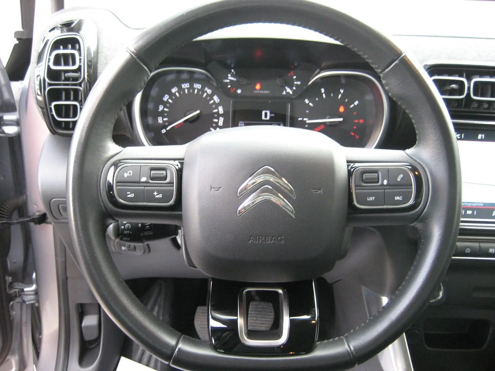 Vue rapprochée du volant noir d'une Citroën C3 Aircross 2022 avec tableau de bord et commandes intégrées visibles.