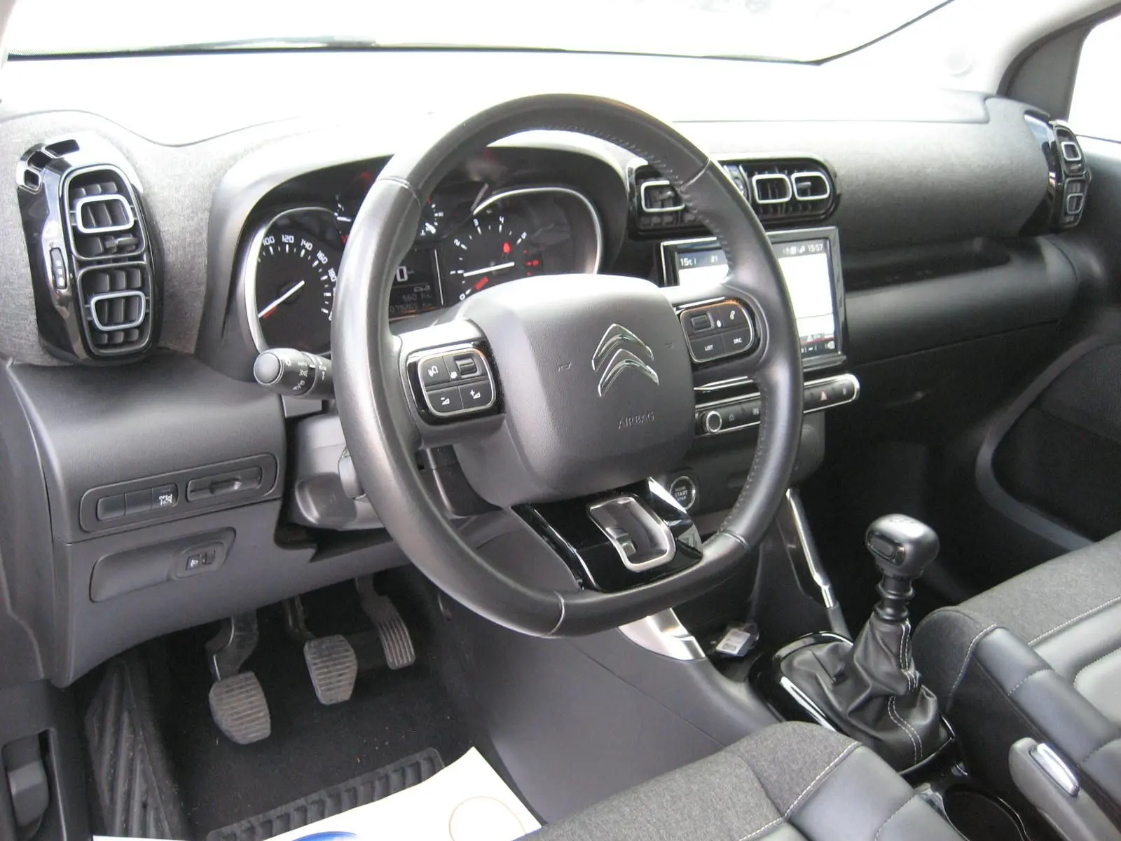 Intérieur du Citroën C3 Aircross gris 2022, vue côté conducteur sur le volant, tableau de bord et levier de vitesses manuel.