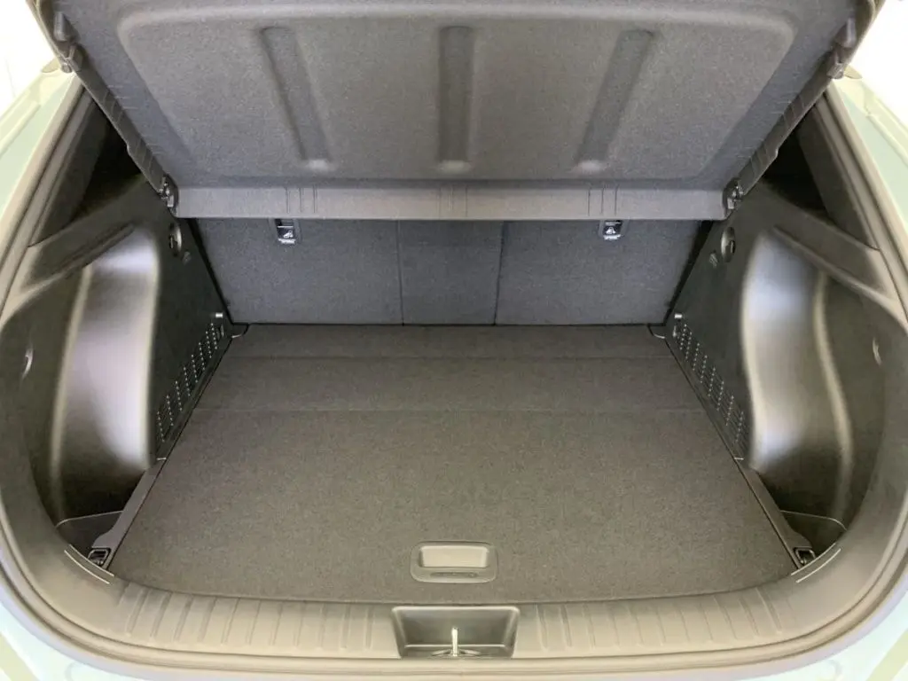 Coffre ouvert du Hyundai Kona Hybrid 2025 en Mirage Green, vue intérieure montrant un espace de chargement propre et spacieux.