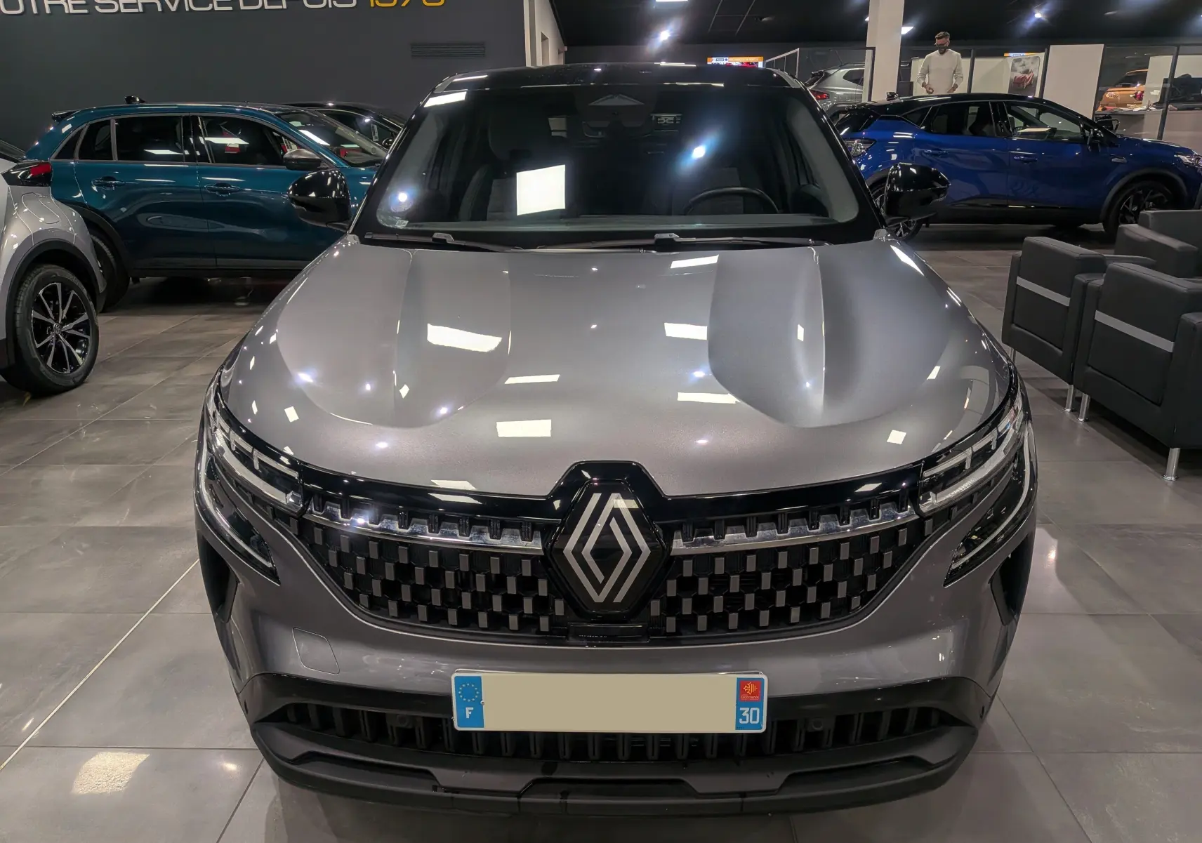 Vue frontale du Renault Austral gris schiste avec toit noir, mettant en valeur sa calandre moderne et son logo central.