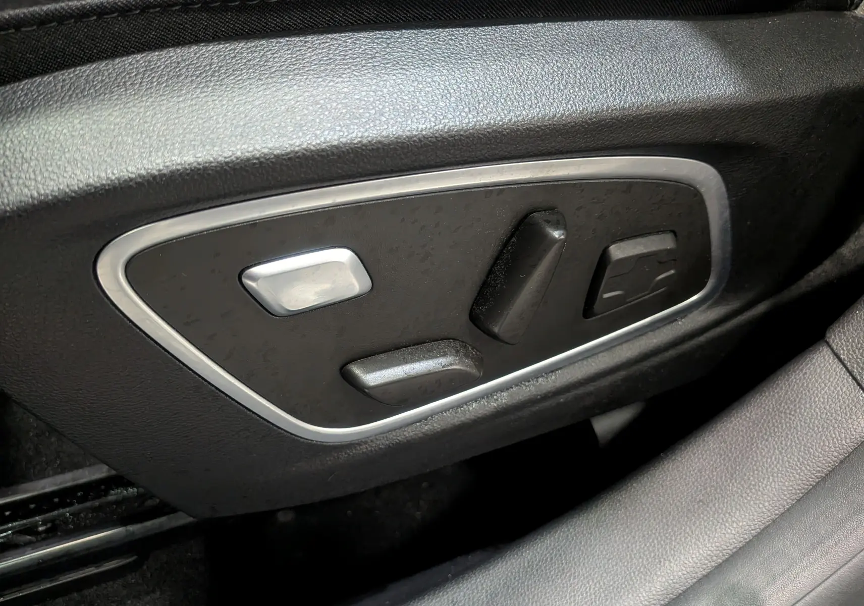 Commandes électriques du siège conducteur en cuir noir du Renault Austral 2024, vue rapprochée côté gauche.