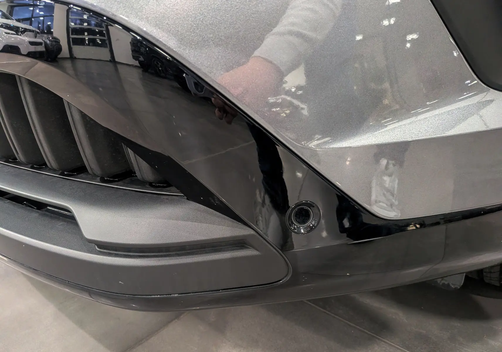 Gros plan sur la partie avant droite gris schiste et noir brillant du Renault Austral 2024 avec capteur de stationnement intégré.