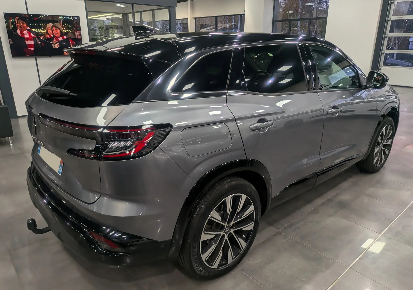 Renault Austral gris schiste avec toit noir, vue 3/4 arrière droit en intérieur, jantes alliage bicolores visibles.